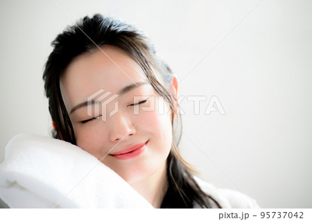 フワフワのタオルを顔に寄せる美しい女性 95737042