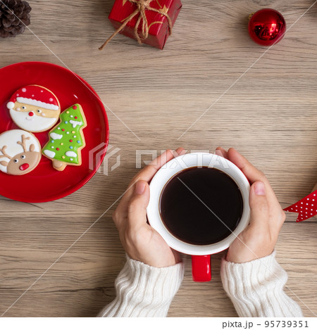 Merry Christmas with woman hand holding coffee cup and homemade cookie on table. Xmas eve, party, holiday and happy New Year concept Merry Christmas with woman hand holding coffee cup and homemade cookie on table. Xmas eve, party, holiday and happy New Year concept 95739351