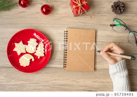 Woman hand writing on notebook with Christmas cookies on table. Xmas, Happy New Year, Goals, Resolution, To do list, Strategy and Plan concept 95739493
