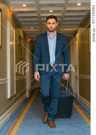 Happy young man with travel bag walking inside hotel 95739982