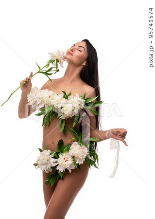 Sensual young woman with flowers on naked body touching face in studio 95741574