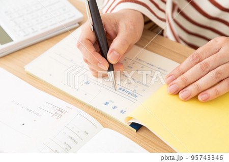 請求書に記入するミドル女性の手元 95743346