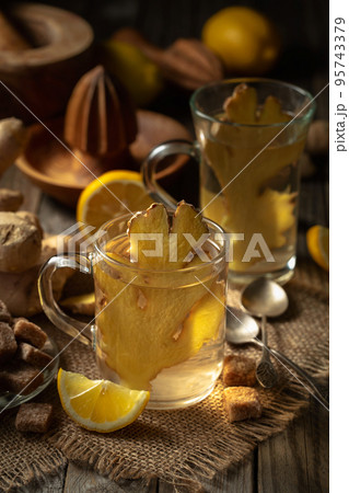 Ginger tea with lemon in a glass cup on an old wooden board. 95743379