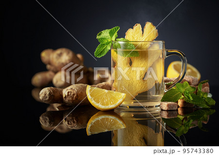 Ginger tea with lemon and mint  on a black reflective background. 95743380