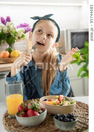 Cute little girl eats fruit salad Cute little girl eats fruit salad 95744085