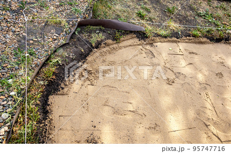 The boundary between wet sand and crushed stone with pebbles on the soil at the construction site, outdoors, in summer 95747716