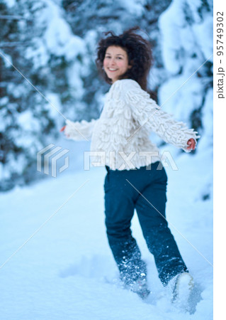 The woman having fun walking in snow covered winter forest The woman having fun walking in snow covered winter forest 95749302