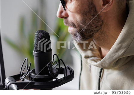 man records a podcast or audio content in a home office. a successful adult man with headphones man records a podcast or audio content in a home office. a successful adult man with headphones 95753630