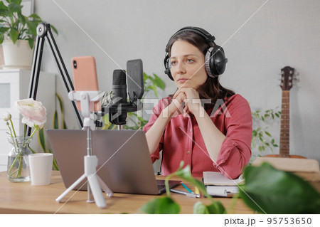 woman in a home office records podcast audio content with a microphone and headphones and a labrador dog woman in a home office records podcast audio content with a microphone and headphones and a labrador dog 95753650