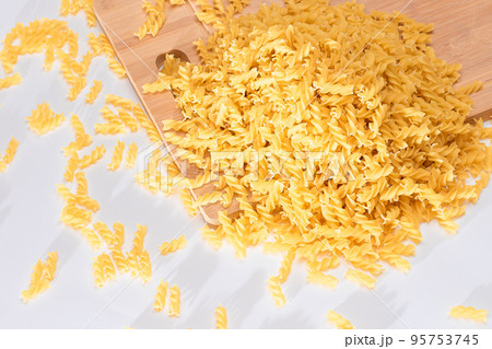 Uncooked Fusilli Pasta Scattered on Wooden Board 95753745