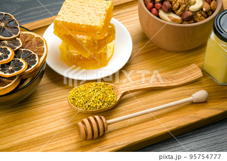 Fresh flower honey of different varieties, pollen and honeycomb with spoons Fresh flower honey of different varieties, pollen and honeycomb with spoons 95754777