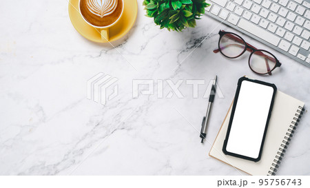 White office desk with keyboard computer, eyeglass, pen, blank screen smart phone, notebook and cup of coffee, Top view with copy space, Mock up. 95756743
