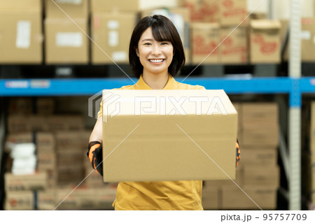 倉庫でダンボールを運ぶ女性スタッフ 倉庫でダンボールを運ぶ女性スタッフ 95757709