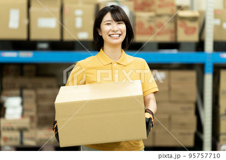 倉庫でダンボールを運ぶ女性スタッフ 倉庫でダンボールを運ぶ女性スタッフ 95757710