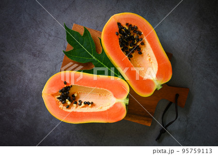 papaya fruits on dark backgroud, fresh ripe papaya slice cut in half tropical fruit with papaya seed and leaf leaves from papaya tree - top view 95759113