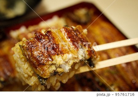 老舗の鰻重大盛（箸持ちアップ） 95761716