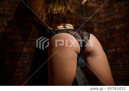 Woman black lace underwear. bdsm A man with a whip in his hands. Toys for adults. Role-playing games. Pain and pleasure. Brick wall. Woman black lace underwear. bdsm A man with a whip in his hands. Toys for adults. Role-playing games. Pain and pleasure. Brick wall. 95763052