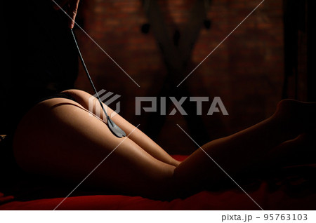 woman with whip on ass. bdsm. A man spanks a partner in the buttocks. Adult toys. 18 plus. Role-playing games. Pain and pleasure. Sexual games. 95763103