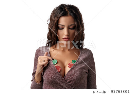 Brunette woman wearing in shiny brown dress. There are some green and red chips on her breast. Isolated on white background. Casino, poker. Close-up. Brunette woman wearing in shiny brown dress. There are some green and red chips on her breast. Isolated on white background. Casino, poker. Close-up. 95763301