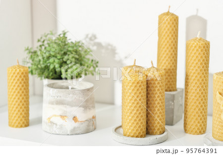 beeswax candles for home decor on a shelf with concrete flower pots. hand made candles made of natural wax with honey fragrance. 95764391
