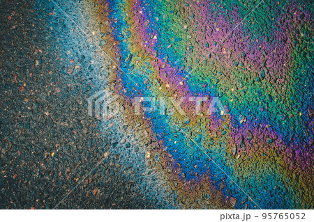 Puddles are contaminated with multicolored streams of oil. Oil stains on wet asphalt. Puddles are contaminated with multicolored streams of oil. Oil stains on wet asphalt. 95765052