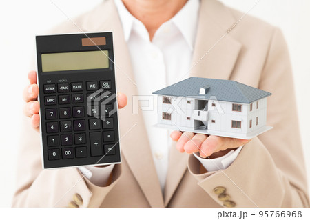 マンションの住宅模型と電卓を持つスーツ姿のミドル女性 95766968