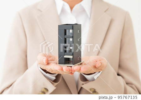 マンションの住宅模型を持つスーツ姿のミドル女性 マンションの住宅模型を持つスーツ姿のミドル女性 95767135