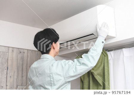 家庭用エアコンの前にいる男性作業員 95767194