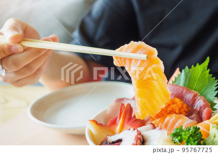 Salmon slice in chopsticks, Eating Sashimi Rice Bowl Chirashi Don Japanese food Salmon slice in chopsticks, Eating Sashimi Rice Bowl Chirashi Don Japanese food 95767725