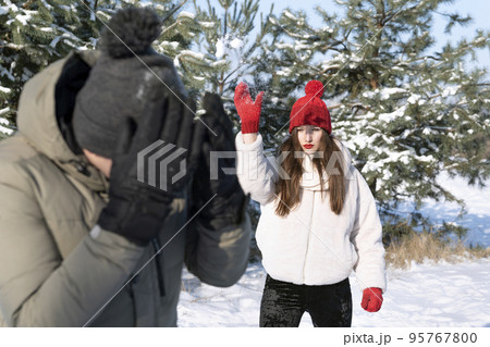 Young woman and boy are playing snowballs in winter forest. Friendship, relationships. Winter holidays 95767800