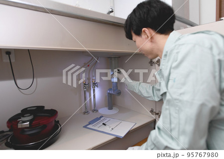 シンク下のチェックする作業服の男性 95767980