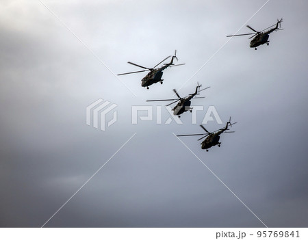 Four military helicopters are flying in battle formation in dark stormy sky. Four military helicopters are flying in battle formation in dark stormy sky. 95769841