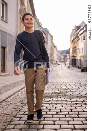 Joyous teenage boy walking along the road 95772305