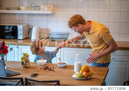 Young father and his cute little son getting ready for breakfast in the kitchen 95772806