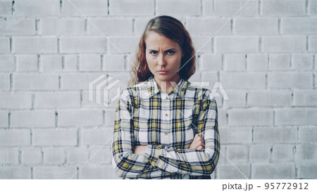 Portrait of angry young lady looking at camera, frowning and shaking her head expressing disappointment and disapproval standing with arms crossed and breathing heavily. Portrait of angry young lady looking at camera, frowning and shaking her head expressing disappointment and disapproval standing with arms crossed and breathing heavily. 95772912
