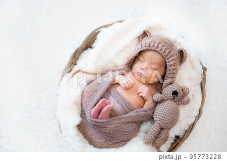 くまのぬいぐるみと一緒に眠る生まれたての赤ちゃんのニューボーンフォト 95773228
