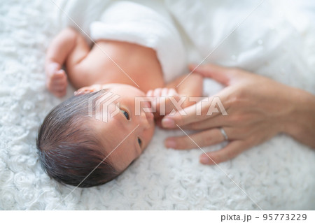 パパに手を添えられて幸せそうな生まれたての赤ちゃん 95773229