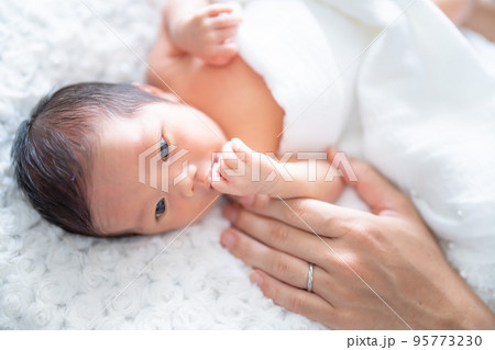 パパに手を添えられて幸せそうな生まれたての赤ちゃん 95773230