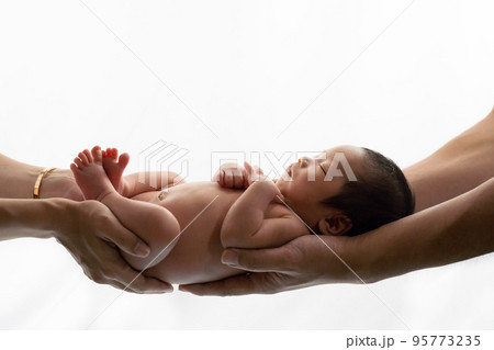 パパとママに支えられて眠る生まれたての赤ちゃんのニューボーンフォト 95773235