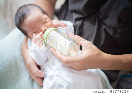 パパに抱っこされてミルクを飲む生まれたての赤ちゃん 95773237
