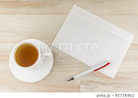 leisurely work in the office - an envelope prepared for writing and sending letters and white Cup with a refreshing green tea are also close by, the view from the top leisurely work in the office - an envelope prepared for writing and sending letters and white Cup with a refreshing green tea are also close by, the view from the top 95776902