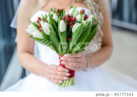 White wedding bouquet of tulips in the hands of the bride blonde White wedding bouquet of tulips in the hands of the bride blonde 95777333