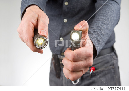 man holds a flashlight in his hand. item for camping and household life man holds a flashlight in his hand. item for camping and household life 95777411