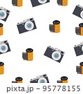Photographic film in a reel and a camera on a white background. 95778155