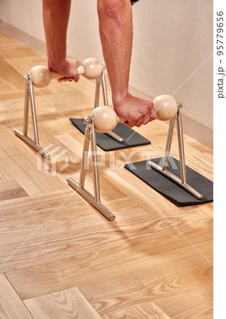Fit man doing a lunge stretch yoga pilates exercise to strengthen and tone his muscles using a reformer in a gym 95779656