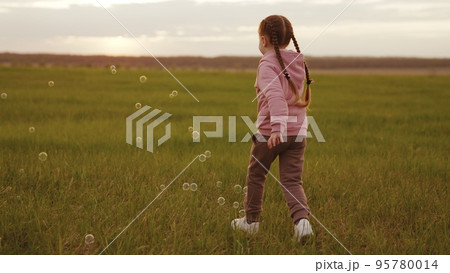 happy child playing park with soap bubbles sunset. cheerful girl run green lawn playing with soap bubbles forest. emotions child girl playing with festive soap balls. positive mood kid park. family. happy child playing park with soap bubbles sunset. cheerful girl run green lawn playing with soap bubbles forest. emotions child girl playing with festive soap balls. positive mood kid park. family. 95780014