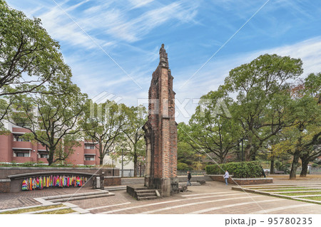 [九州・長崎] 千羽鶴と煉瓦制の浦上天主堂遺壁の周りに観光する人たち。 95780235