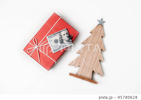 How To Spend, Christmas budget and saving concept. Xmas gift box, Stack of dollar bills and wooden Christmas tree on white table How To Spend, Christmas budget and saving concept. Xmas gift box, Stack of dollar bills and wooden Christmas tree on white table 95780628