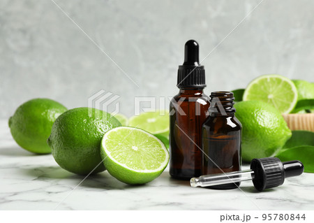 Lime essential oil and citrus fruits on marble table 95780844
