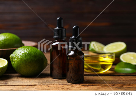 Lime essential oil and cut citrus fruits on wooden table 95780845